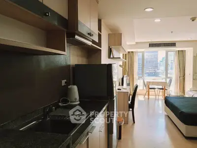 Modern studio apartment with open kitchen and city view, featuring sleek cabinetry and natural light.