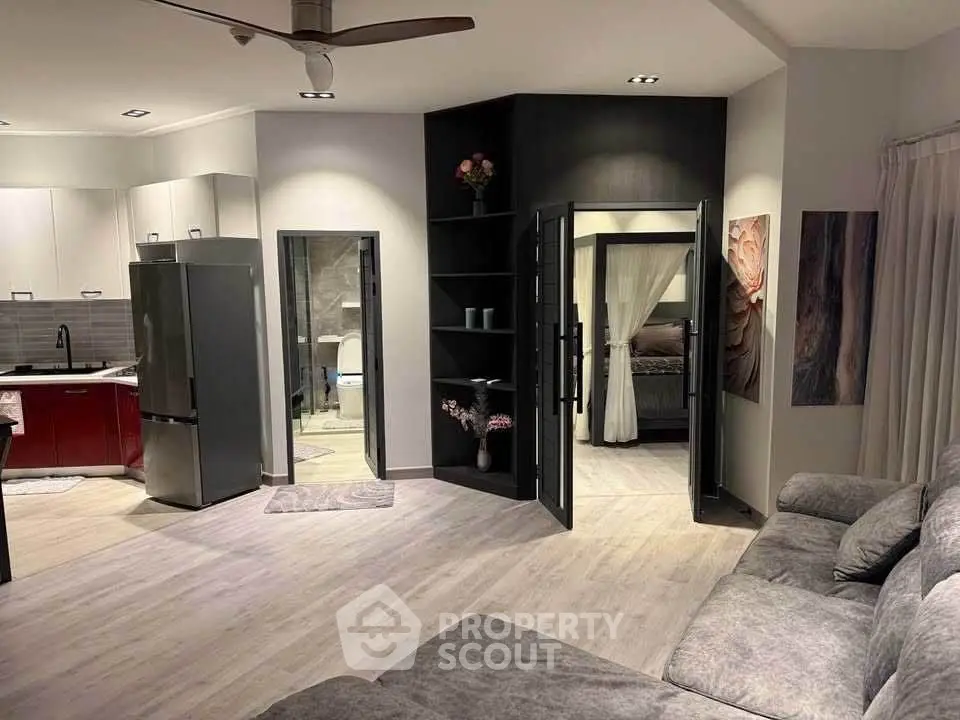 Modern open-plan living room with sleek kitchen and cozy bedroom view