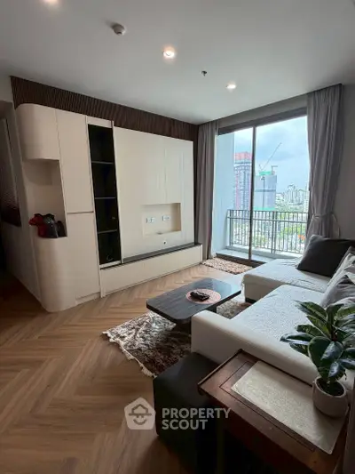 Modern living room with large windows and city view, featuring stylish furniture and elegant decor.
