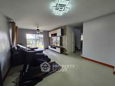 Spacious living room with modern lighting and treadmill, perfect for relaxation and fitness.
