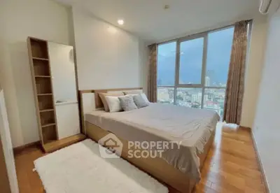 Spacious bedroom with city view and modern furnishings in high-rise apartment.
