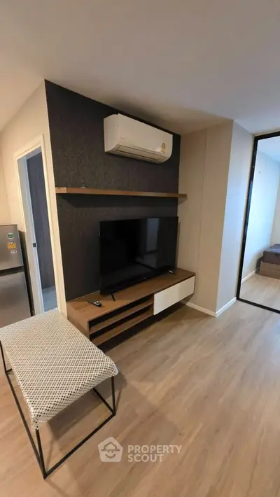 Modern living room with sleek TV unit and air conditioning, featuring stylish wood flooring.