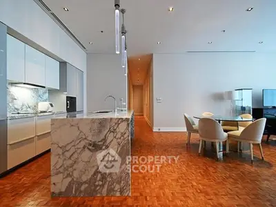 Luxurious modern kitchen with marble island and dining area in open layout.