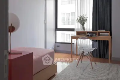 Modern bedroom with stylish desk and chair, large window, and cozy decor
