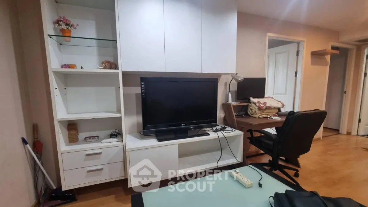 Modern living room with TV, desk, and shelving unit in cozy apartment