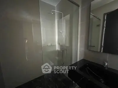 Modern bathroom with sleek glass shower and dark marble flooring