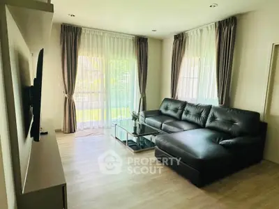 Spacious living room with modern leather sectional and large windows for natural light.