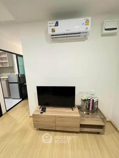Modern living room with air conditioning and TV unit, adjacent to a sleek kitchen.