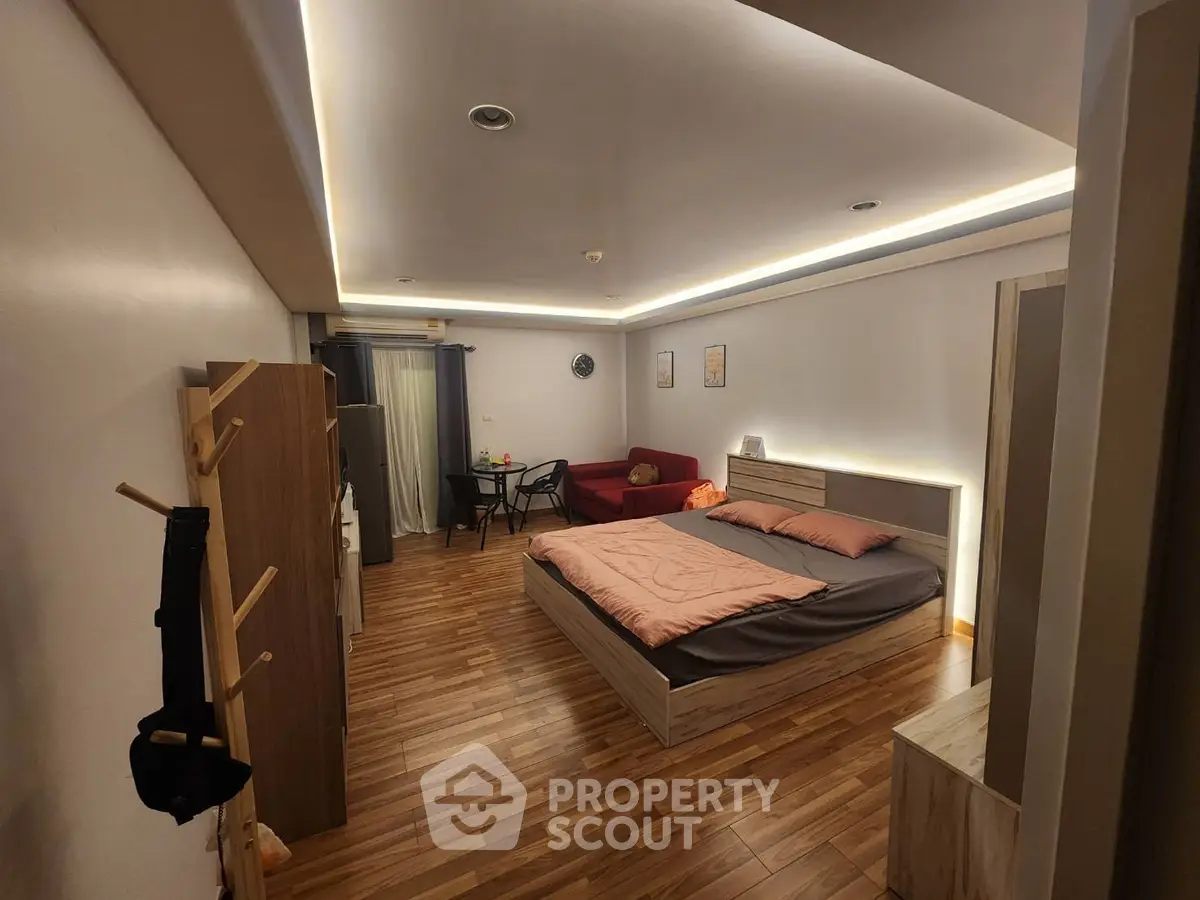 Spacious modern bedroom with stylish lighting and cozy seating area