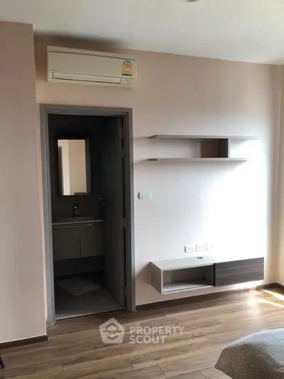 Modern bedroom with wooden flooring, air conditioning, and built-in shelves.