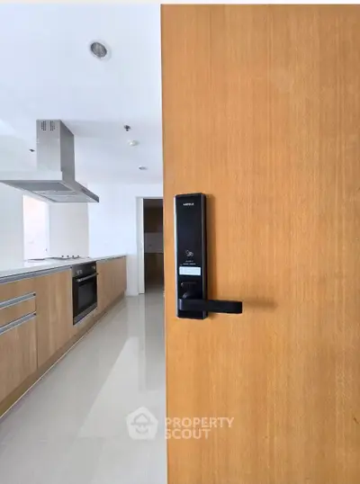 Modern kitchen with sleek appliances and wooden cabinetry, featuring an electronic door lock for enhanced security.