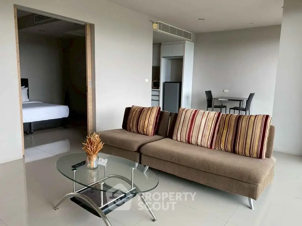 Modern living room with stylish sofa and glass coffee table in open-plan apartment.