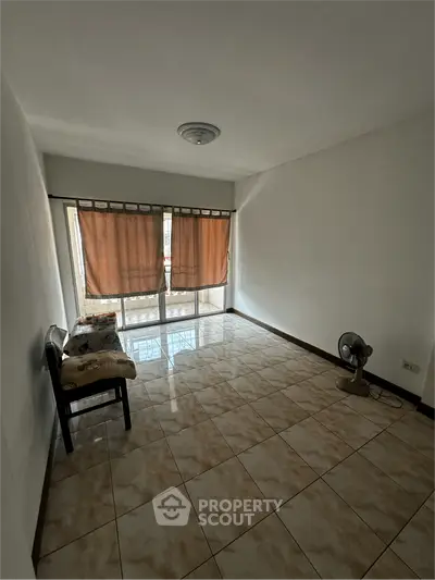 Spacious living room with tiled flooring and large windows for natural light.