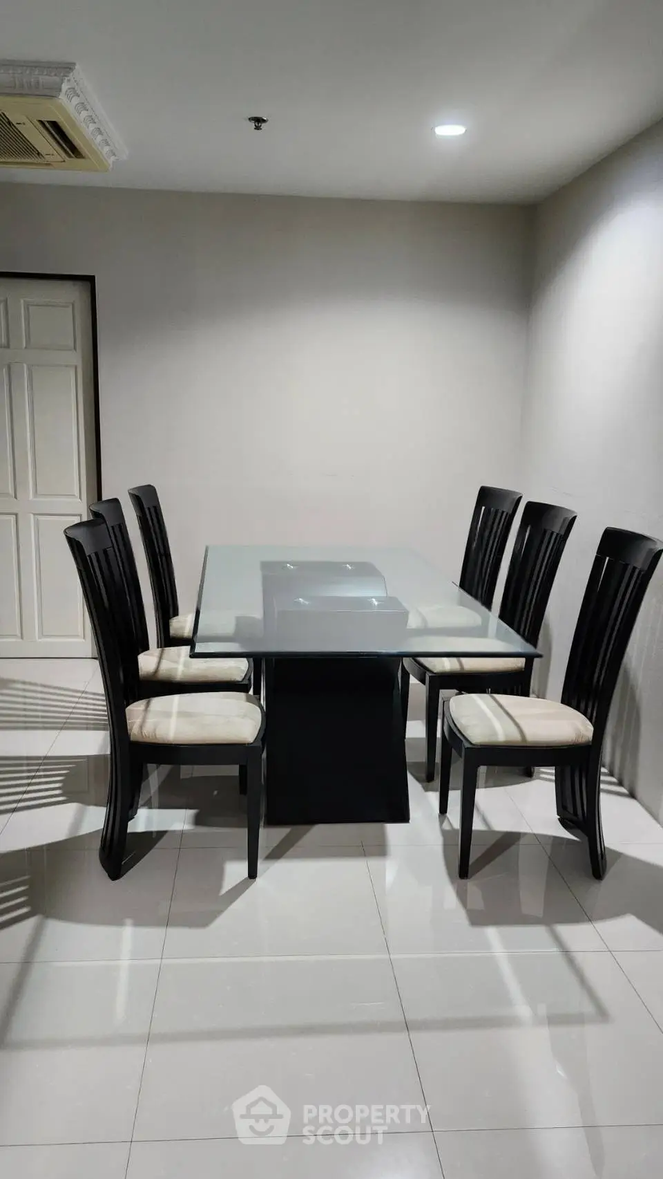 Elegant dining room with modern glass table and six stylish chairs, perfect for family gatherings.