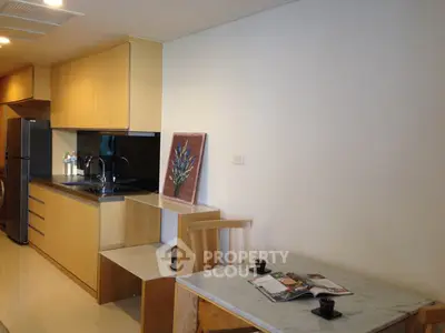 Modern kitchen with sleek wooden cabinets and marble dining table in a cozy apartment.