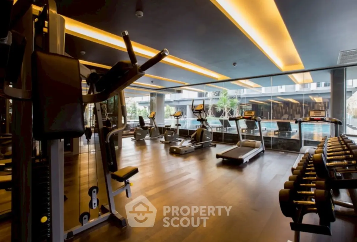 Luxurious gym with modern equipment and pool view in upscale real estate property.