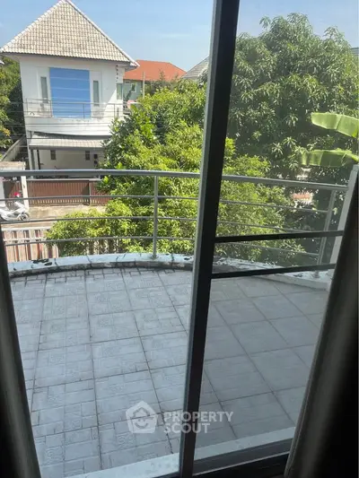 Spacious balcony with lush garden view in a modern residential area.