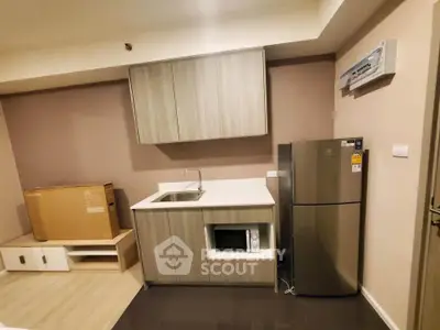 Modern kitchen with sleek cabinetry, stainless steel fridge, and microwave in a compact layout.