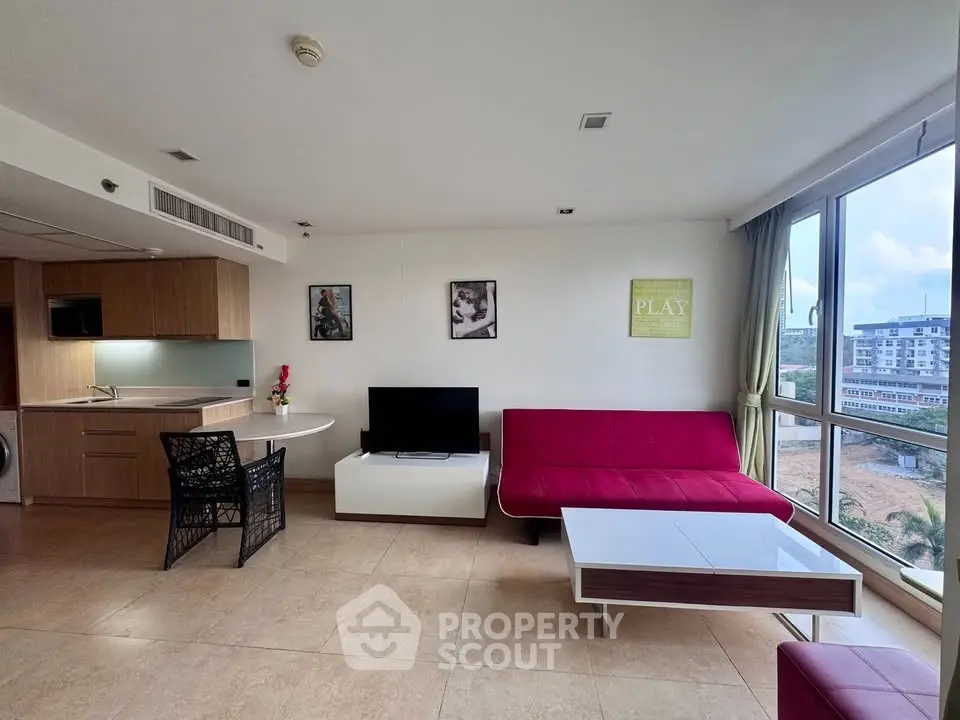Modern living room with open kitchen, red sofa, and large windows offering city views.