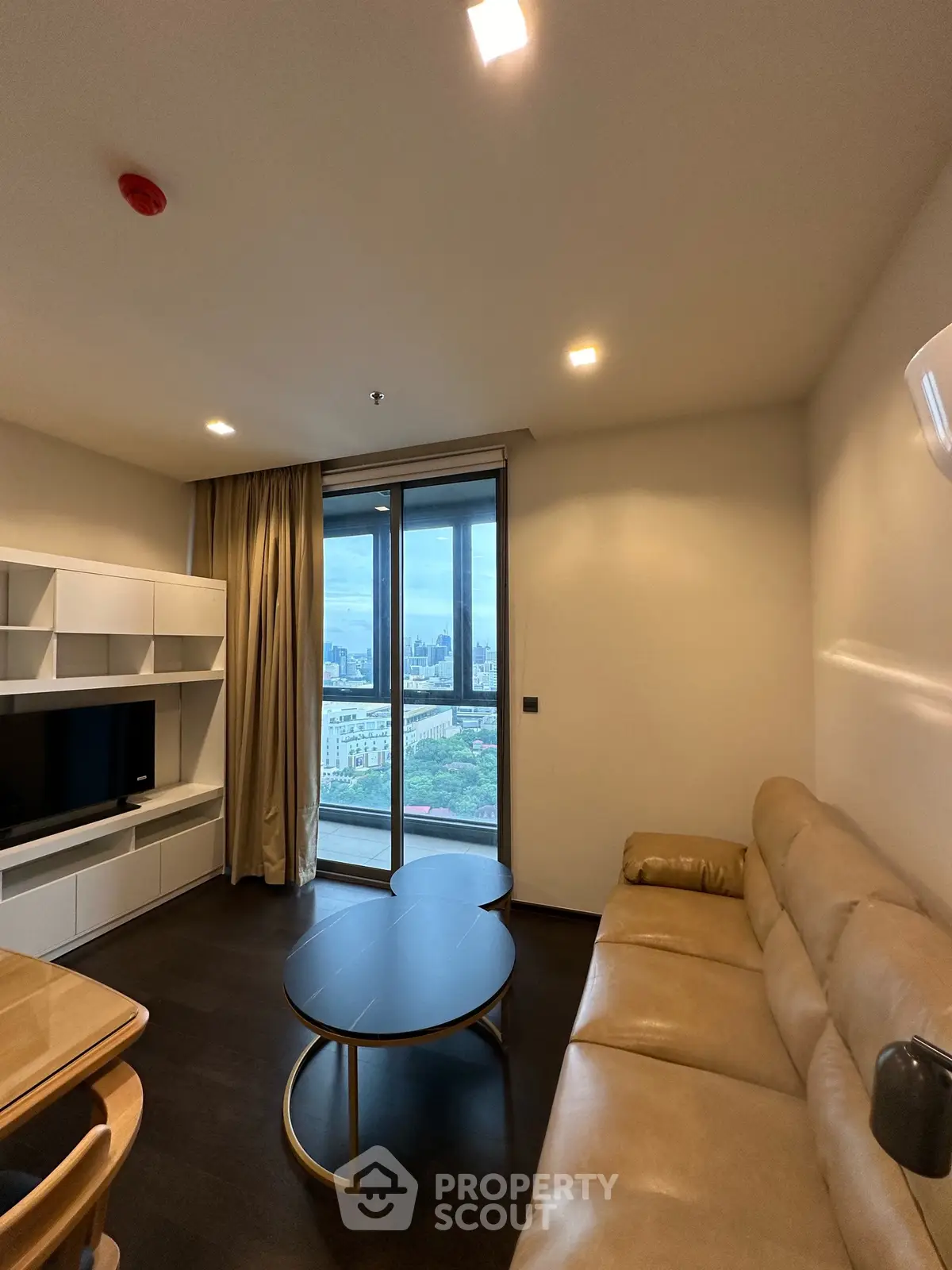 Modern living room with city view, featuring sleek furniture and large windows for natural light.