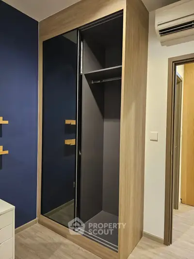 Modern bedroom with sleek mirrored wardrobe and air conditioning unit