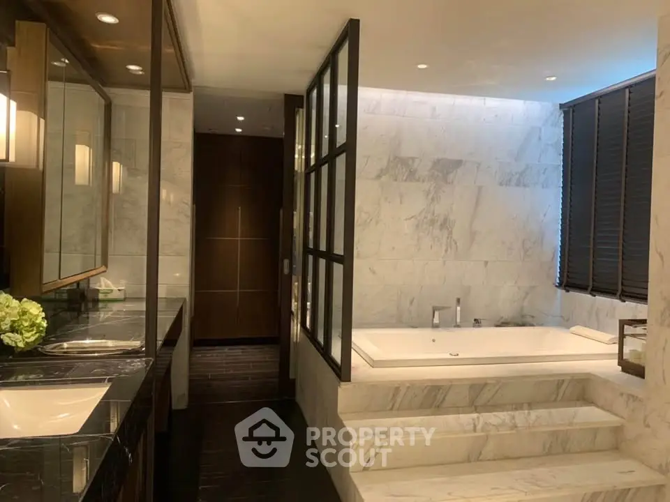 Luxurious marble bathroom with sunken bathtub and elegant lighting