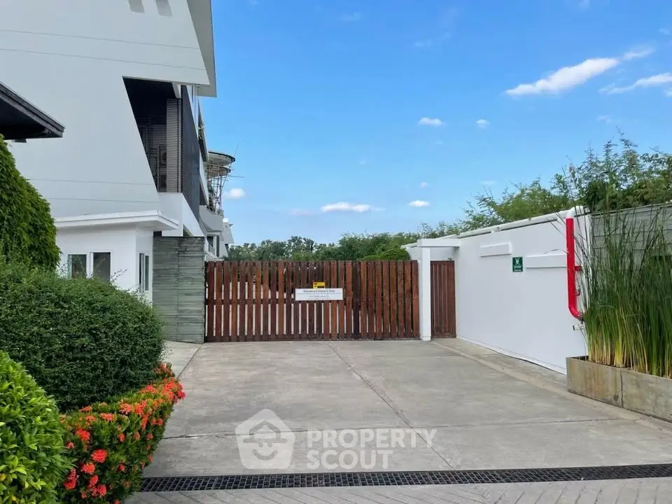 Modern gated entrance with lush greenery and clear blue sky