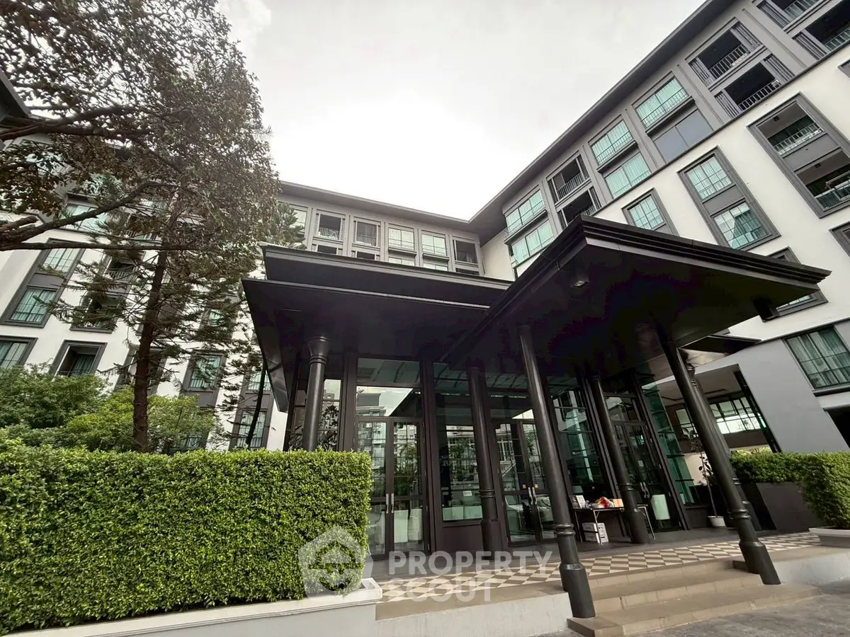 Modern apartment building entrance with lush greenery and sleek design