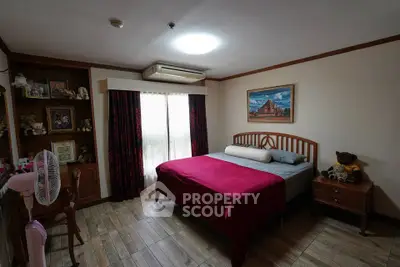 Cozy bedroom with wooden flooring, large window, and stylish decor in a modern apartment.