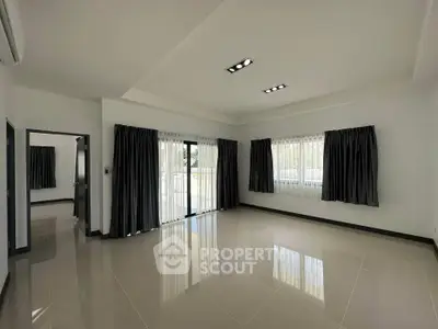 Spacious unfurnished living room with large windows and modern lighting