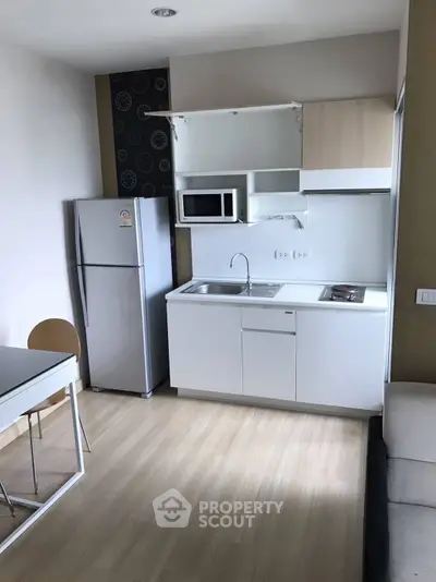 Modern compact kitchen with sleek appliances and dining area in a stylish apartment.