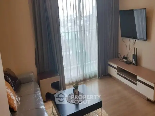 Modern living room with large window and wall-mounted TV in stylish apartment.