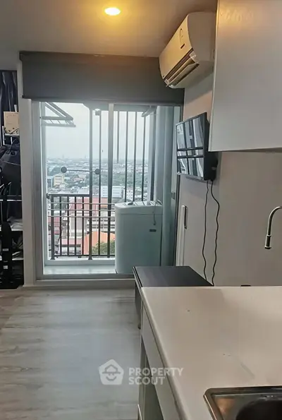Modern apartment with balcony view, sleek kitchen, and air conditioning, perfect for urban living.