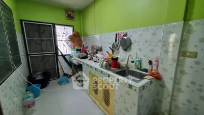 Cozy kitchen with vibrant green walls and tiled backsplash, featuring a compact layout and essential appliances.