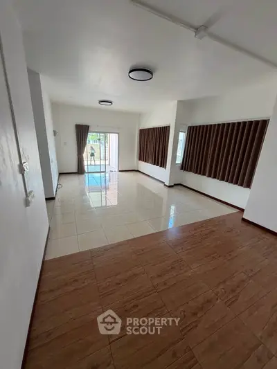 Spacious living room with large windows and elegant tile flooring, perfect for modern living.