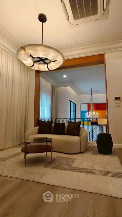 Elegant living room with modern chandelier and cozy seating area, perfect for relaxation and entertaining.