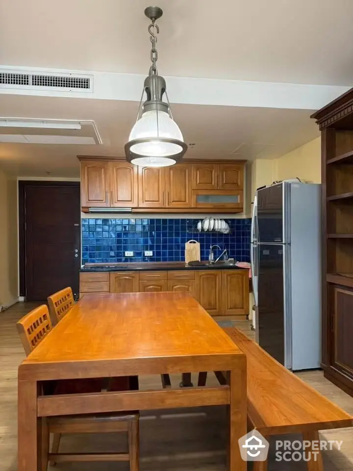 Charming kitchen with wooden cabinetry and blue tile backsplash, featuring a spacious dining table and modern appliances.