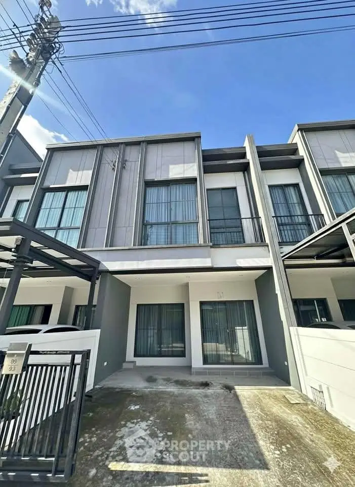 Modern townhouse exterior with large windows and driveway under clear blue sky.