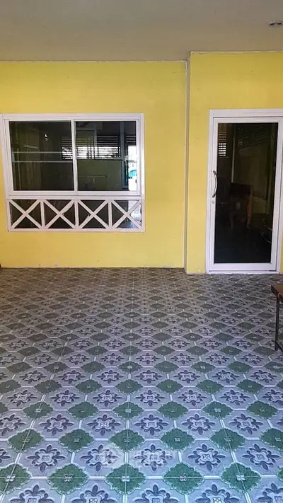 Charming patio with vibrant yellow walls and decorative tile flooring, perfect for outdoor relaxation.