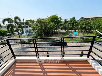 Spacious balcony with scenic view of lush greenery and residential street.