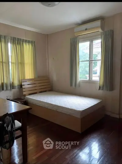 Cozy bedroom with wooden flooring, single bed, and air conditioning, perfect for a comfortable living space.