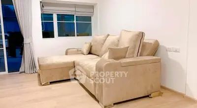 Spacious living room with elegant beige sectional sofa and large window, perfect for relaxation and entertaining.