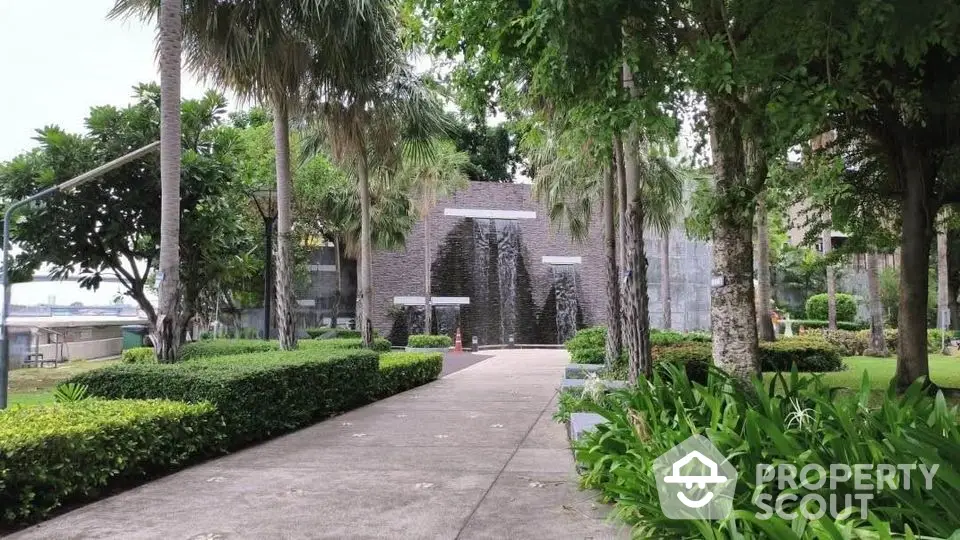 Lush garden pathway leading to a modern building with water feature