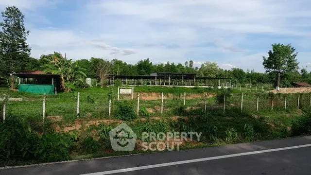 Expansive green land with fencing, ideal for development or agriculture.