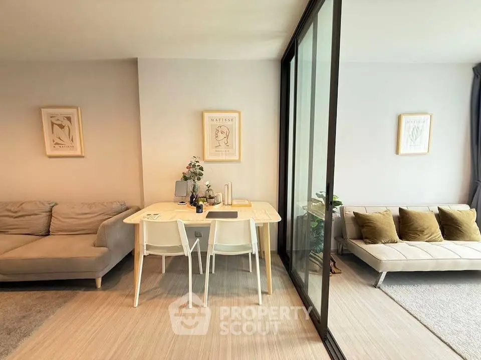 Modern living room with stylish decor and glass partition, featuring cozy seating and elegant dining area.