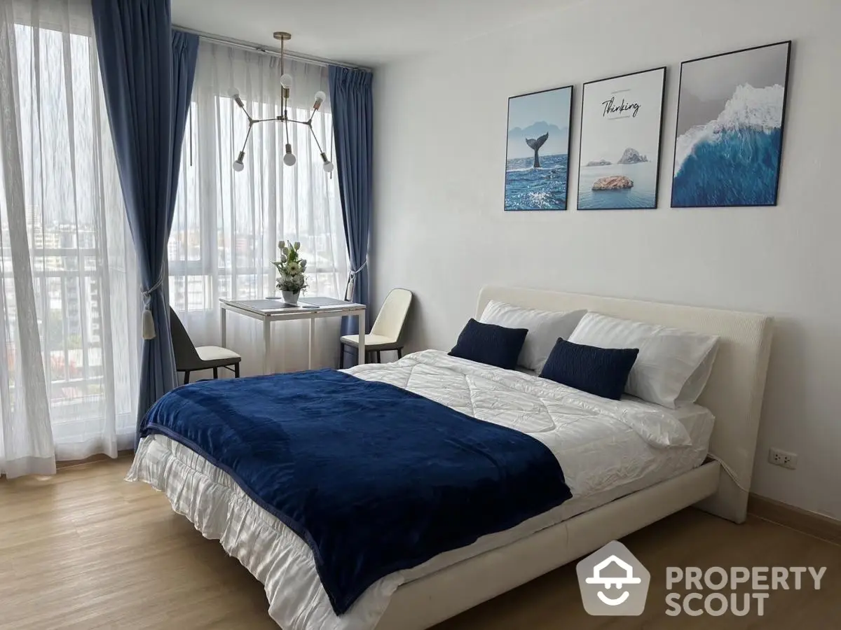 Modern bedroom with stylish decor and city view, featuring elegant blue accents and natural light.