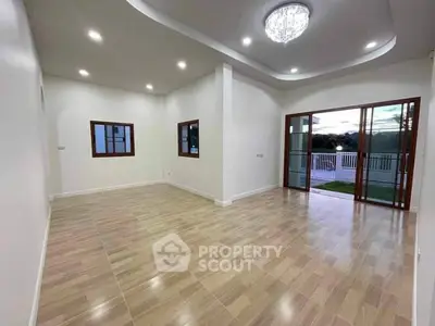 Spacious living room with elegant lighting and balcony access, perfect for modern living.