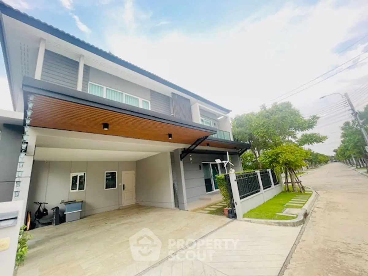 Modern two-story house with spacious driveway and lush greenery in a serene neighborhood.