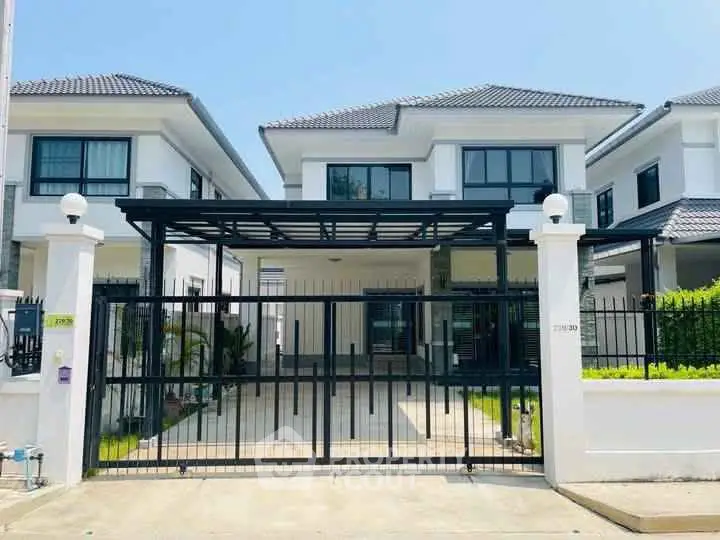 Modern two-story house with gated driveway and sleek design.