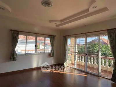 Spacious sunlit room with large windows and balcony view in a modern home.